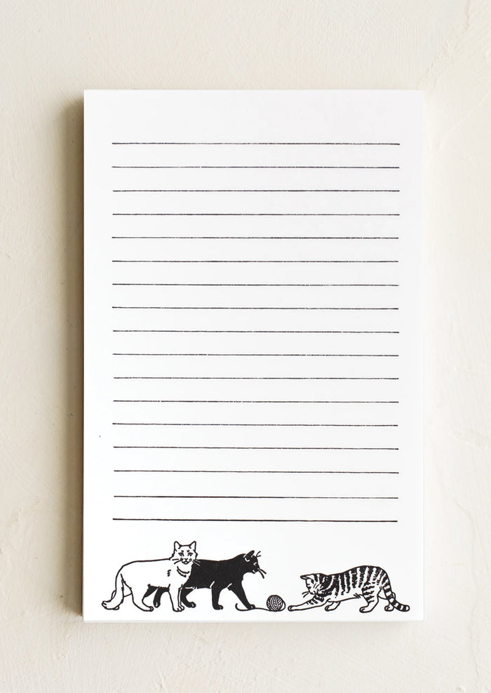 A white notepad with black lines and cat print with yarn.
