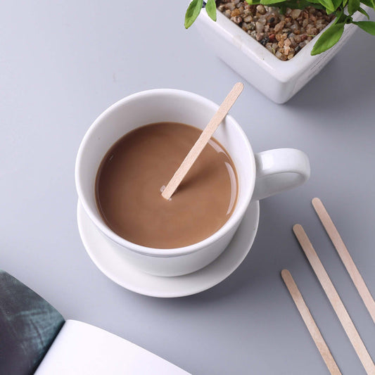 Cup of coffee with a stir stick on a gray surface