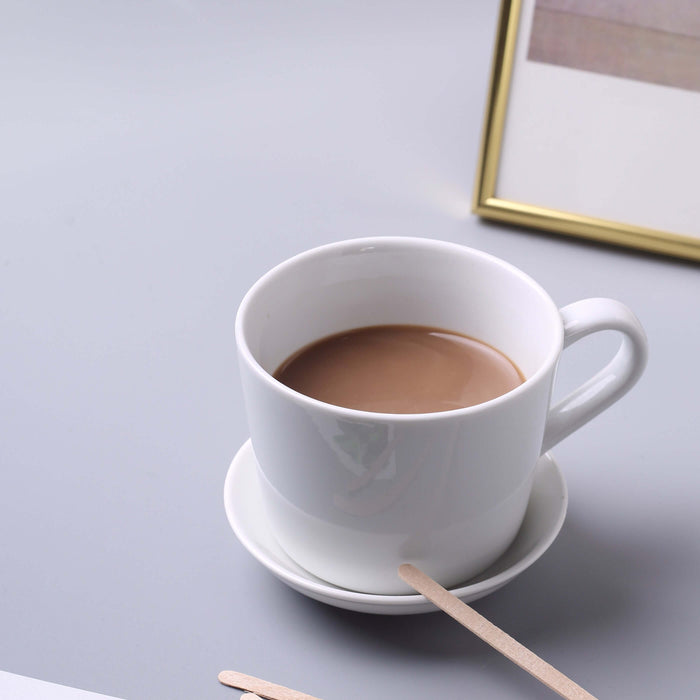 White cup of coffee on a saucer with a wooden stirrer.