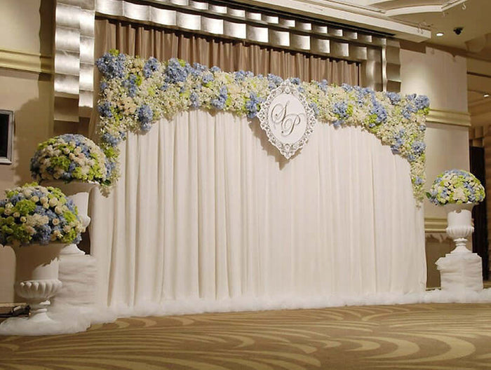 Elegant floral wedding backdrop with blue and white flowers, featuring a decorative monogram.