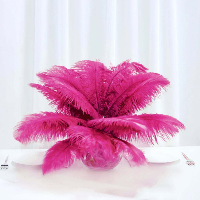 Pink feather centerpiece in glass vase on white table.