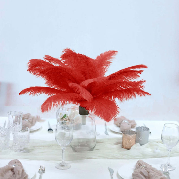 Red feather centerpiece in a glass vase on a dining table.