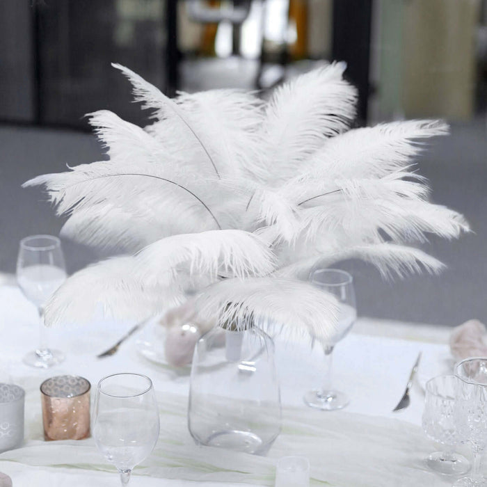 White feather arrangement in a glass vase on a dining table.