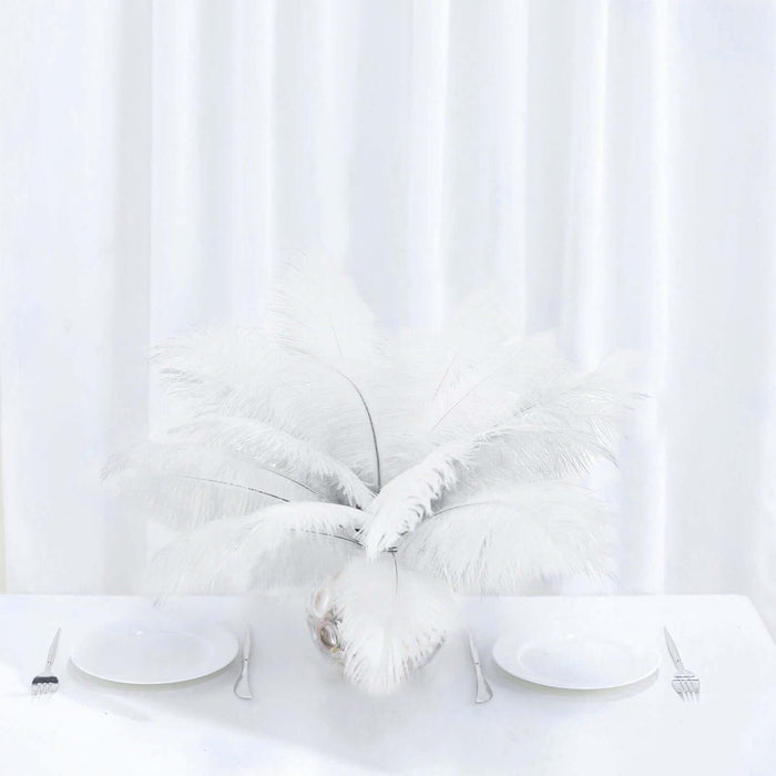 White feather centerpiece on a dining table with two plates and cutlery.