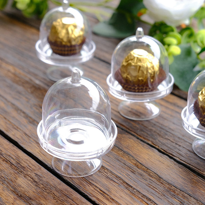 Miniature clear dessert domes with gold-wrapped chocolates inside.