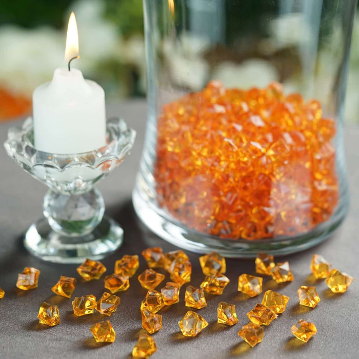 Orange crystal decoration pieces with a candle on a table.