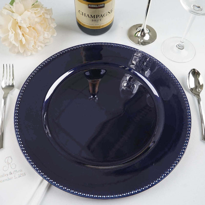 Navy blue dinner plate with silver beaded rim on a dining table setting.
