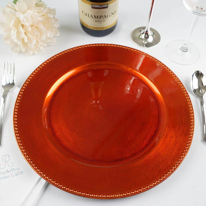 Orange charger plate with decorative beaded edge on a dining table.