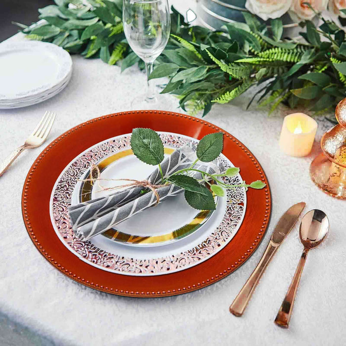 Elegant table setting with decorative plates, cutlery, and greenery accents.