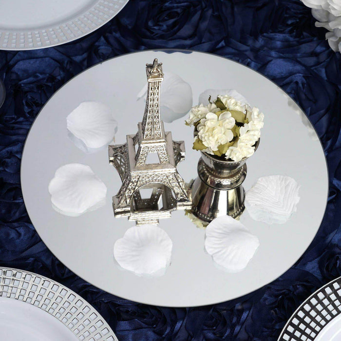 Eiffel Tower centerpiece with flowers and petals on a mirrored table setting.