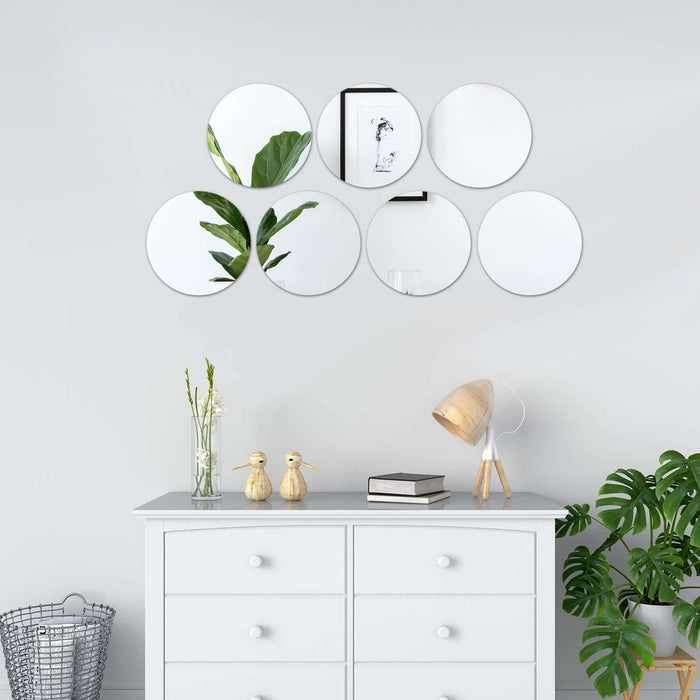 Decorative round mirrors arranged above a white dresser with plants and decor.