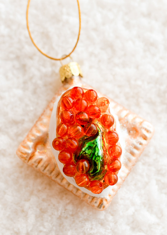 A glass ornament of a cracker with cream and caviar.