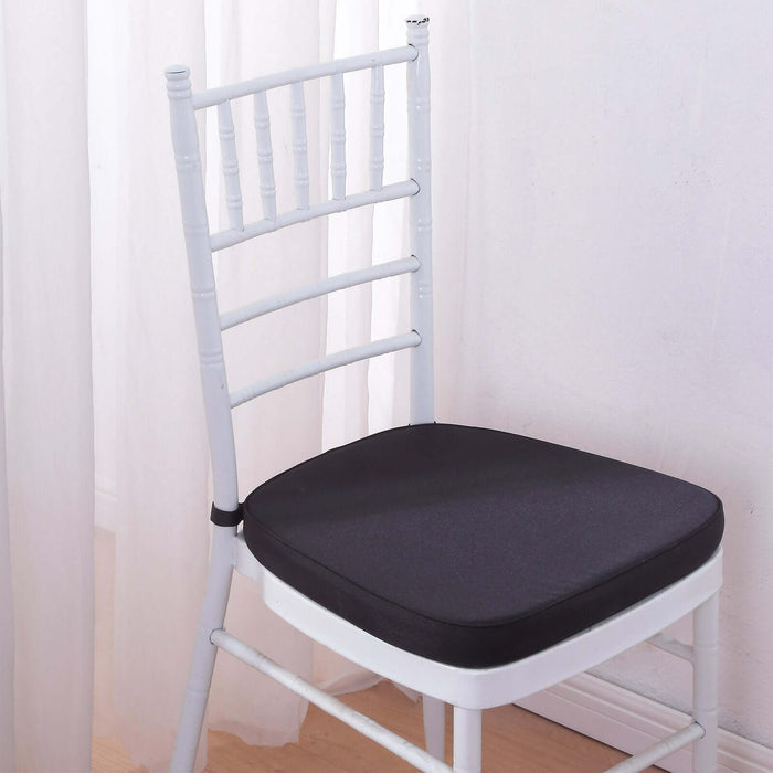 White chair with a black cushion against a light backdrop.