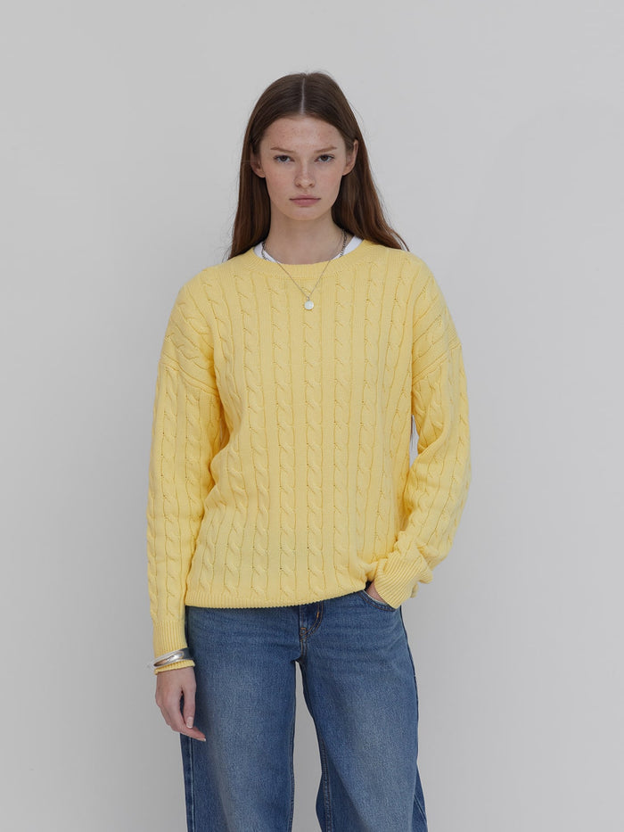 A model wears women's cotton cable knit sweater in butter yellow by One Dna brand