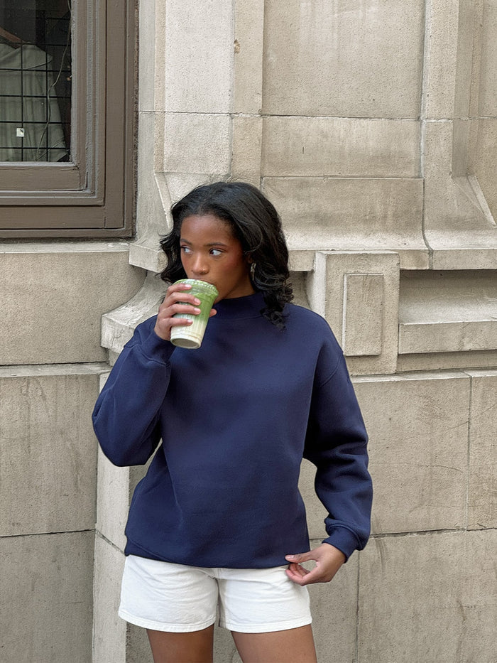 female model holding matcha wears mock neck sweatshirt in navy by one dna