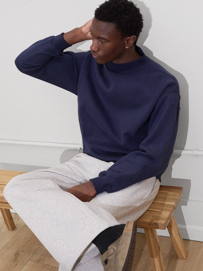 male model sits on bench wearing one dna mock neck and sweatpants