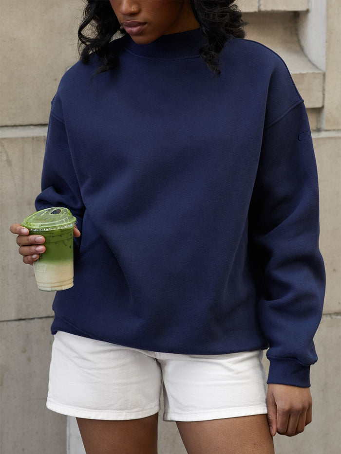 female model holding matcha wears mock neck sweatshirt in navy one dna