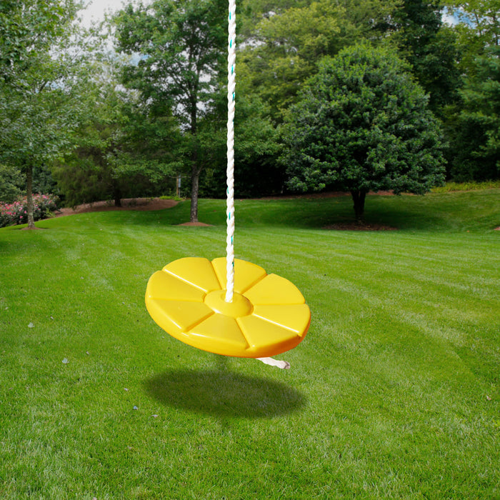 Yellow round disc swing with heavy-duty rope hanging outdoors over green grass and trees