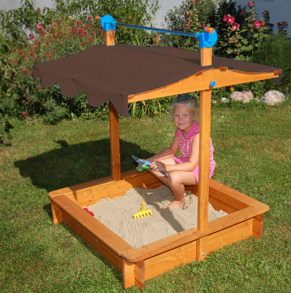 Felix Sandbox With Adjustable Roof with wooden frame and brown canopy, child playing inside on sand in garden setting