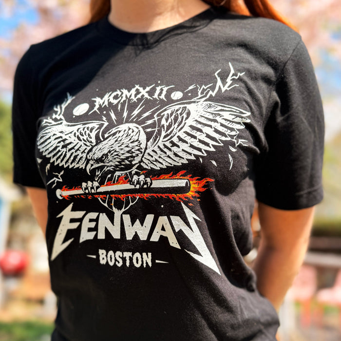 woman wearing Black unisex t-shirt featuring a heavy metal-style graphic of a screaming eagle with spread wings gripping a flaming baseball bat, with the word "FENWAY" in Metallica-inspired lettering, "BOSTON" below, and "MCMXII" in Roman numerals above — The Red Seat original design