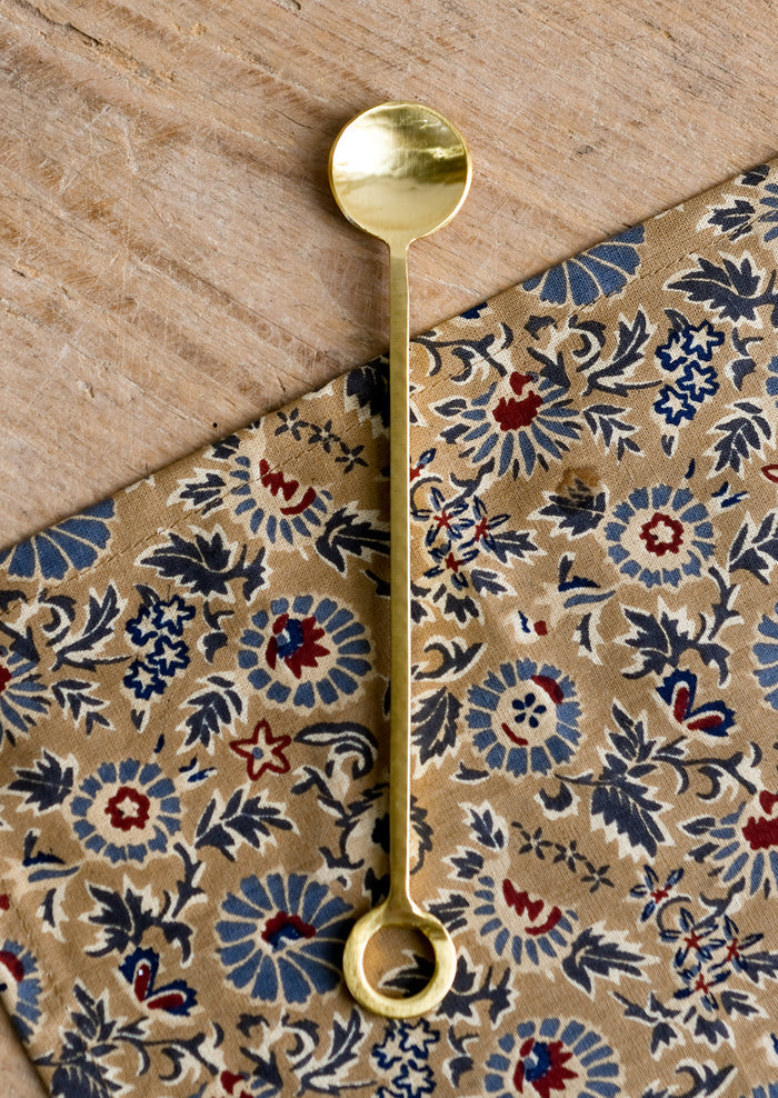 Gold finish cocktail spoon with circular loop at end of handle.