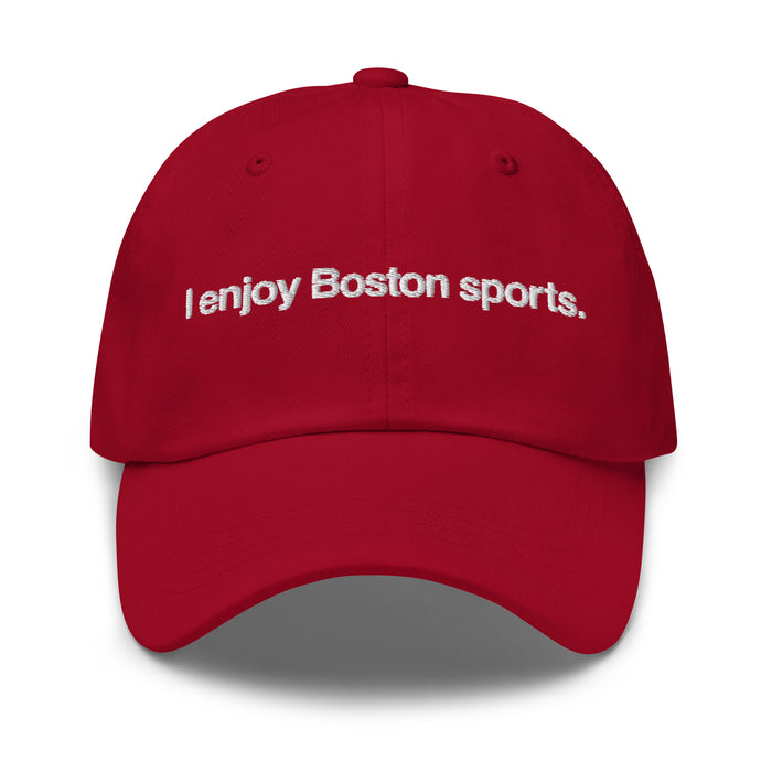 red baseball cap with "i enjoy boston sports" embroidered in white helvetica font