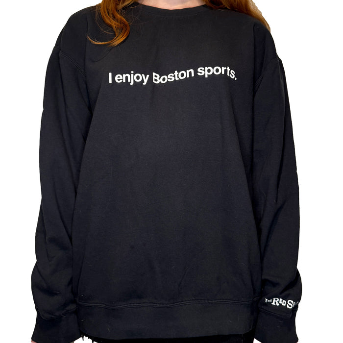 woman wearing black unisex crewneck sweatshirt with the words i enjoy boston sports in white on the front