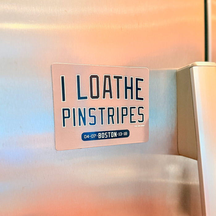 Refrigerator magnet with text 'I LOATHE PINSTRIPES' on a stainless steel fridge