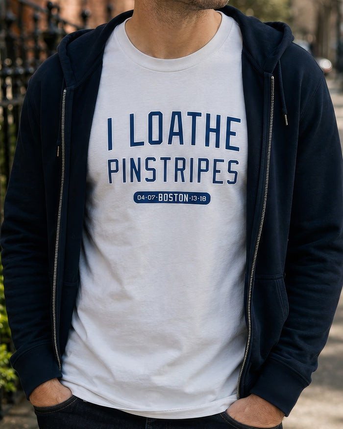 A man wearing a navy blue zip-up hoodie over a grey t-shirt with the text 'I LOATHE PINSTRIPES' and a small 'BOSTON' graphic in navy blue.