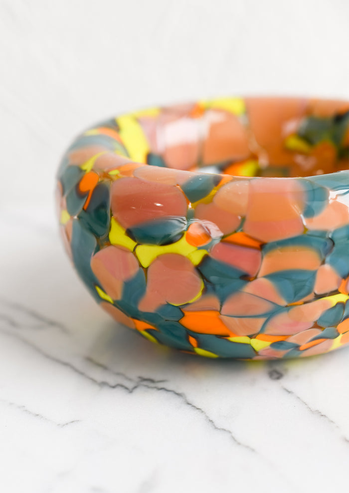 A speckled multicolor glass bowl in teal, peach, orange and yellow.