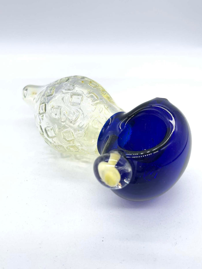 Photo of a large fumed spoon pipe with a blue head and a bulbous fumed body that tapers to a small mouthpiece, against a white background. The piece is facing head side right, and a mushroom implosion bubble can be seen on its left side (facing camera).
