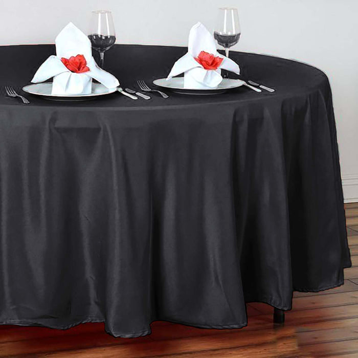 Elegant black tablecloth draped over round table with glassware and napkins.
