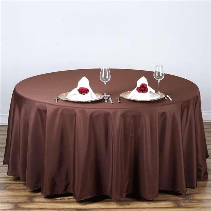 Brown round tablecloth draped over a table set for two with elegant dinnerware.