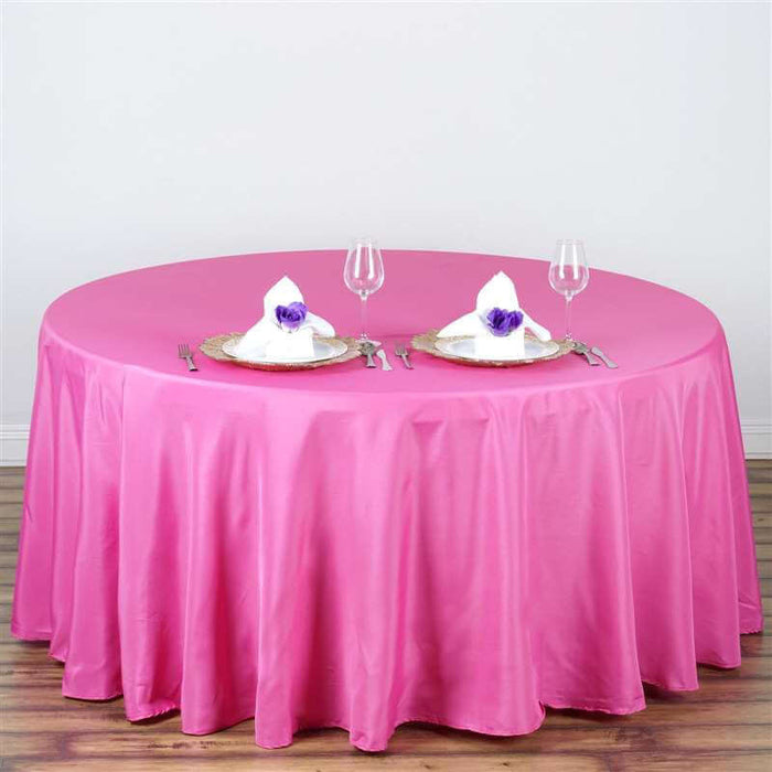 Pink round tablecloth draped over a circular table with elegant place settings.