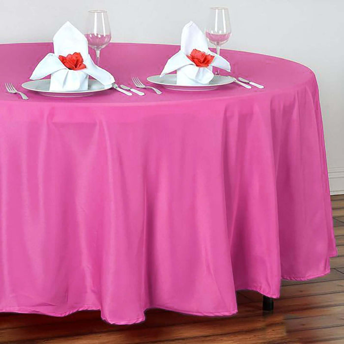 Pink tablecloth draped over a round table with elegant place settings.