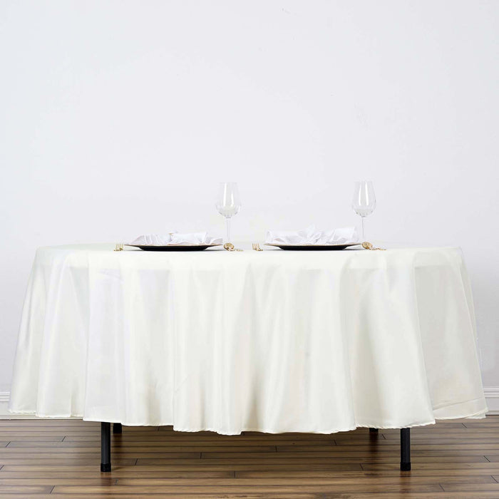 Round table set with elegant white tablecloth and dinnerware.