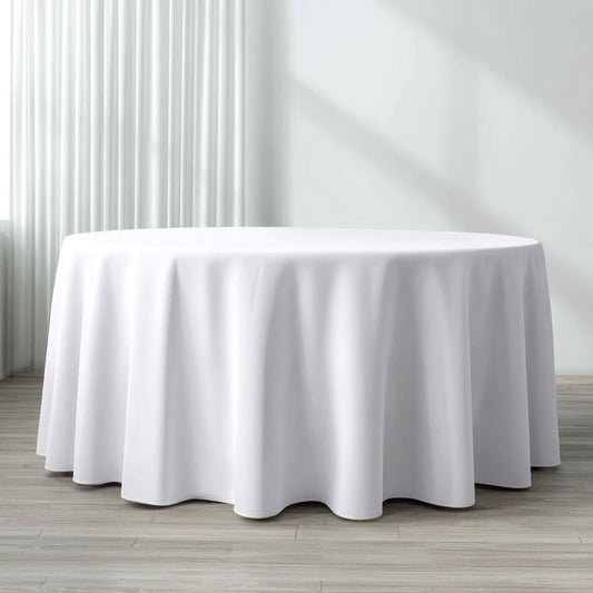 Round table covered with a white tablecloth in a bright interior setting.