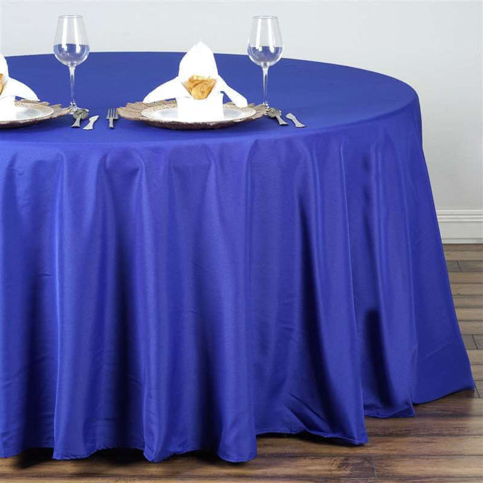 Royal blue tablecloth draping a round table set for dining.