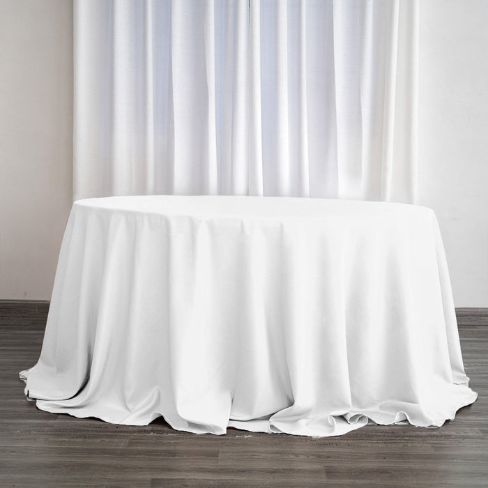 White round table with a draped tablecloth in a bright interior setting.