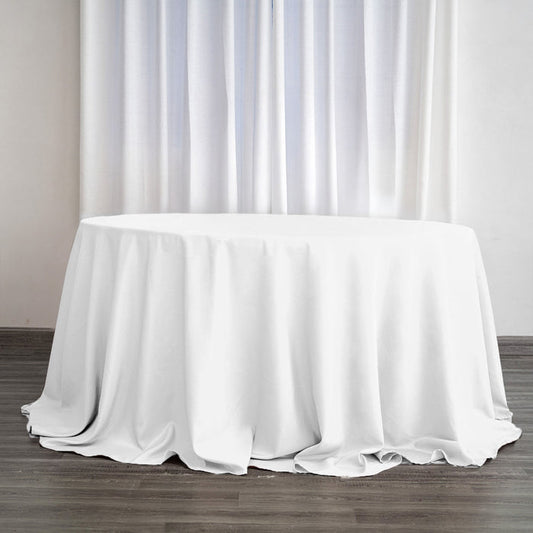 White round table with a draped tablecloth in a bright interior setting.