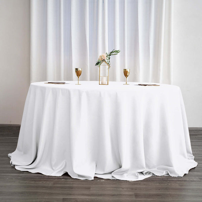 Elegant round table set with a white tablecloth, gold accents, and floral centerpiece.