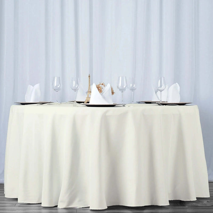 Elegant round dining table set with white tablecloth and glassware.