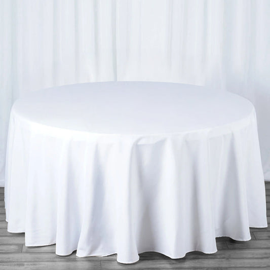 Round white tablecloth draped over a table in a studio setting.