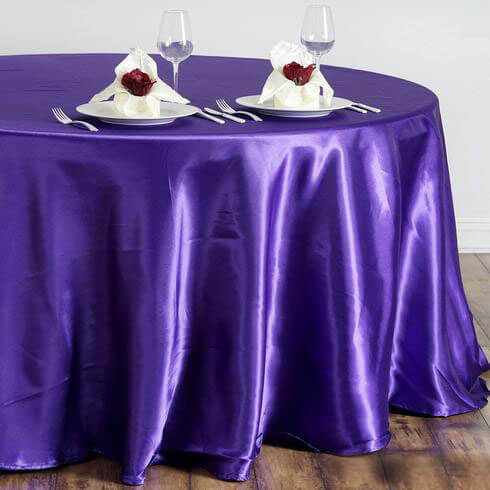 Purple satin tablecloth with elegant dinner setup and rose-adorned napkins.