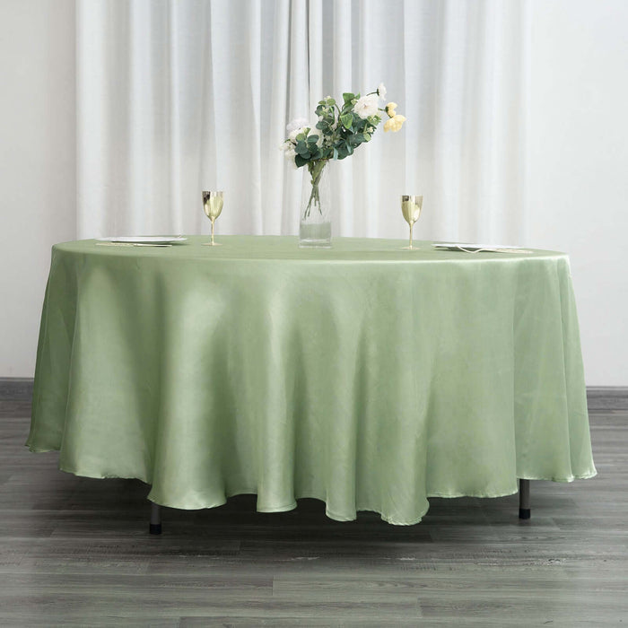 Elegant green tablecloth draped over a round table with floral centerpiece and glasses.