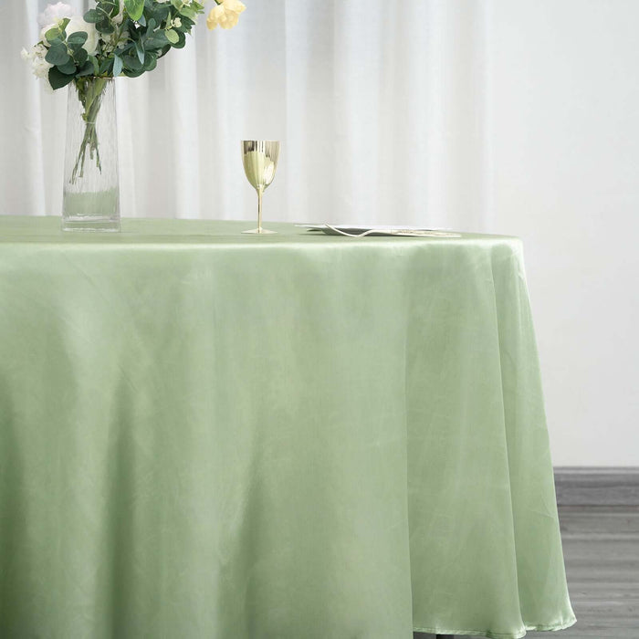 Green tablecloth draped over a table with a vase and glass in a softly lit room.