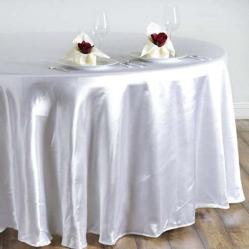 Elegant white satin tablecloth with rose-adorned napkins on a round table.