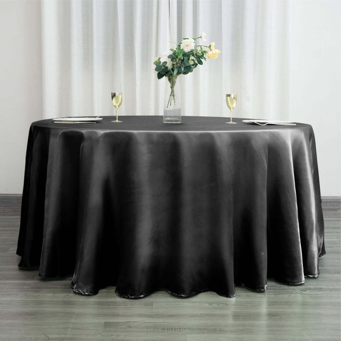 Round black tablecloth draped over a table with a floral centerpiece.