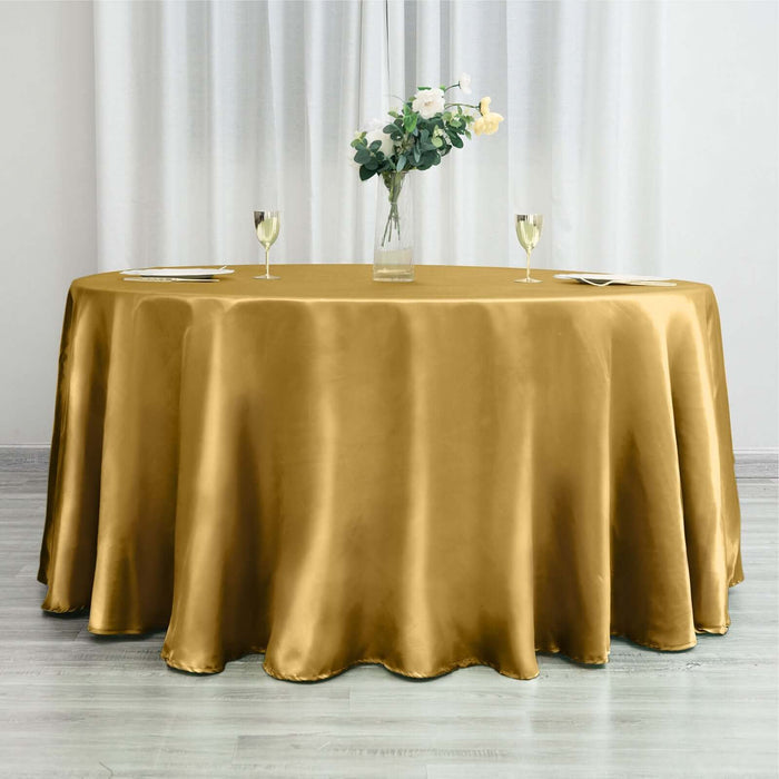 Gold satin tablecloth draped elegantly on a round table with floral centerpiece.