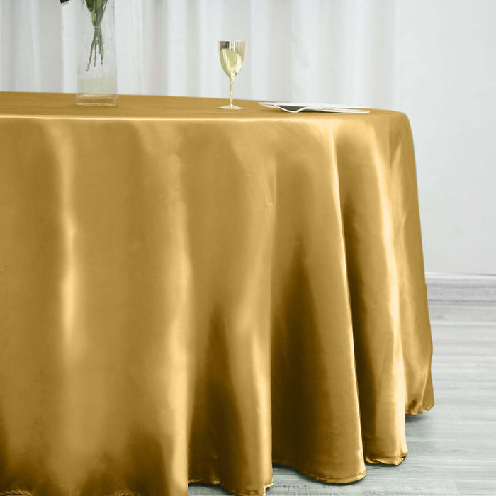 Gold satin tablecloth on a dining table with glass and vase.
